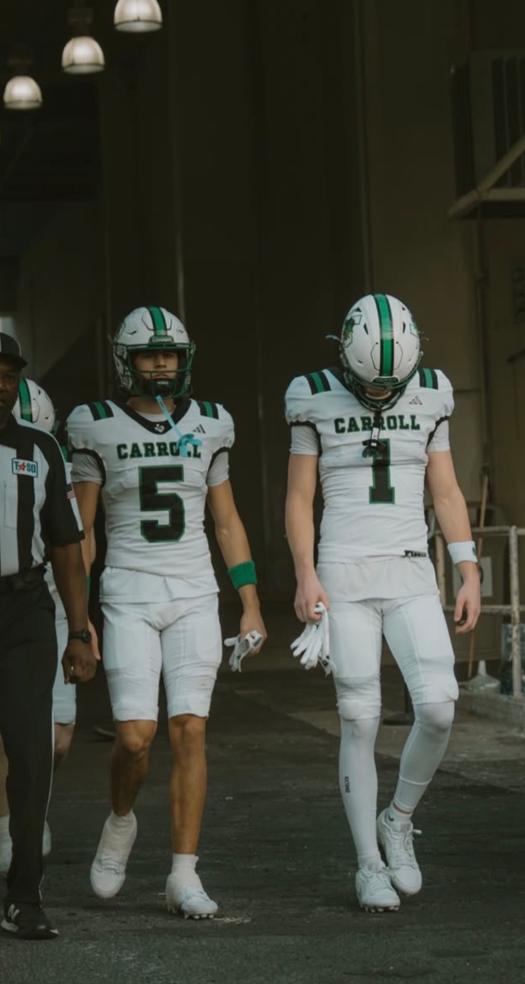 Two Southlake Carroll players in white uniforms walking out of the tunnel before kickoff